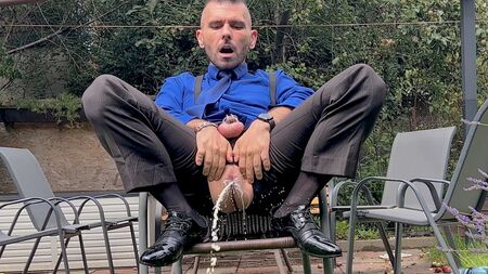 Ein Mann im Anzug mit eingesperrtem Schwanz spielt an seiner Männermuschi herum und pinkelt in der Öffentlichkeit in hauchdünnen Socken