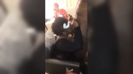 Ältere schwarze Stiefmutter lutscht auf einer Party einem Stripper den Schwanz