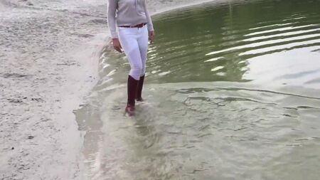 Ich gehe im See spazieren und weiche meine braunen Reitstiefel ein