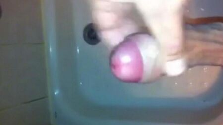 Das Kind steht in der Dusche und wichst mit dem Handabbau am Ende den Penis aus dem Penis